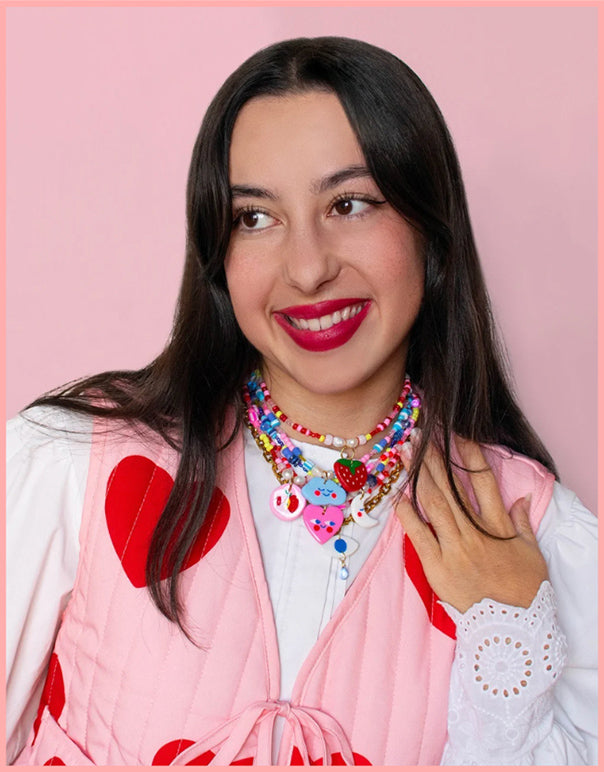 Woman wearing a colorful necklace with a pink background