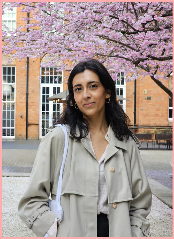 Woman standing in front of a cherry blossom tree with a pink border